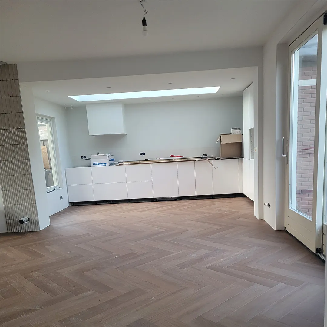 Nieuwe open keuken en woonkamer met visgraat parket en een lichtkoepel in het plafond
