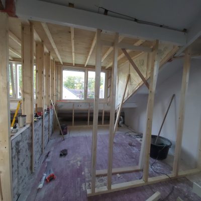 Nieuwe houten binnenwanden in aanbouw onder een schuin dak, met een dakraam en isolatie
