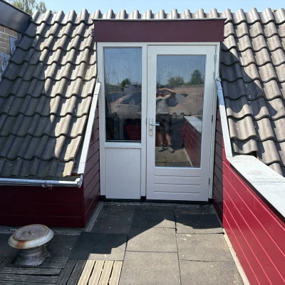 Balkon na renovatie met nieuwe rode gevelbekleding en een deur