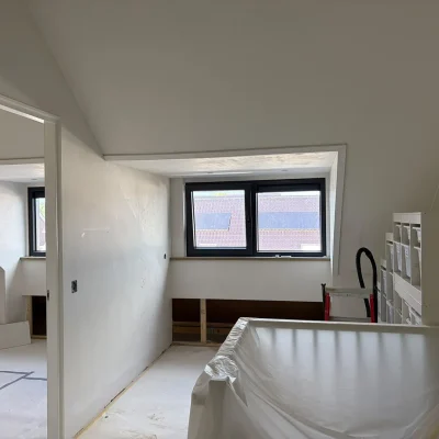 Nieuwe zolderkamer in aanbouw met twee nieuwe ramen naast elkaar in de dakkapel, wanden nog in afwerking
