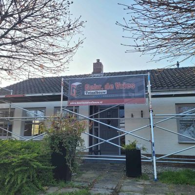 Voorgevel van de woning tijdens de renovatie, met een spandoek van Gebr. de Vries
