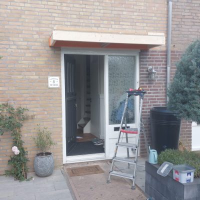 Voordeur met nieuwe houten luifel boven de entree van een woning