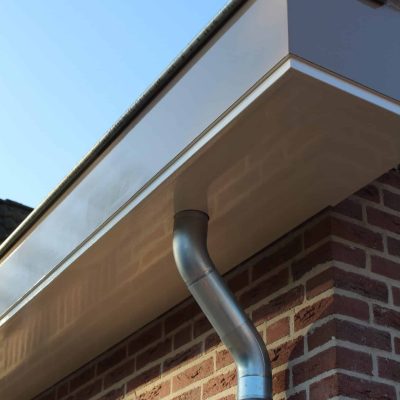 Detail van een nieuwe lichte dakgoot en regenpijp op een bakstenen gevel