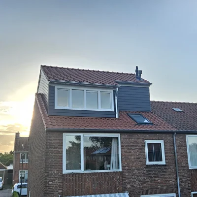Woning met nokverhoging bij zonsondergang, met dakraam zichtbaar in het dakvlak