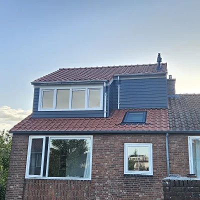 Woning met nokverhoging in de avondzon, gezien vanaf de straat