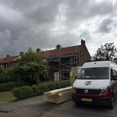 Bouwmaterialen en een bestelbus van Gebr. de Vries voor een woning tijdens de verbouwing