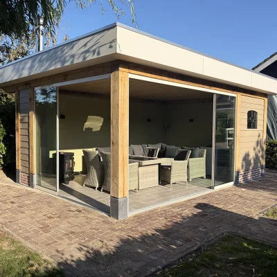 Tuinkamer gezien vanaf het terraspad, met glazen schuifwanden en een loungeset