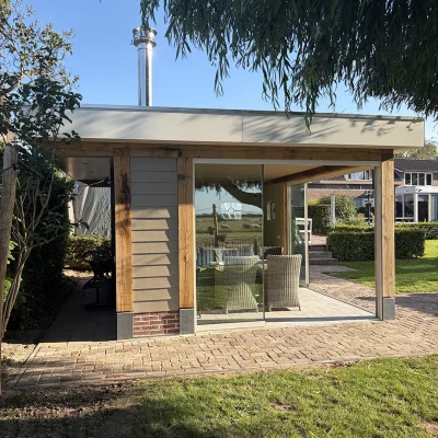 Tuinkamer met eiken balken en glazen schuifwanden, met zicht op het open veld