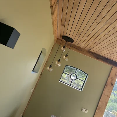 Interieur van de tuinkamer met stalen ramen met roedeverdeling en hanglampen met gloeilampen