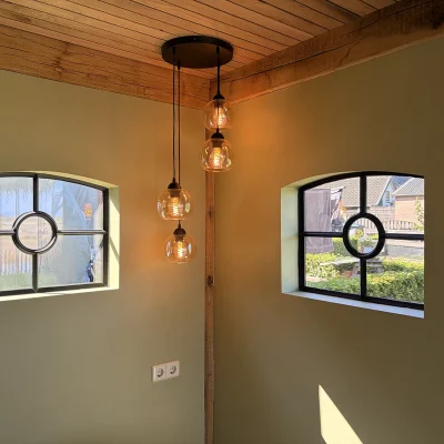 Interieur van de tuinkamer met houten plafond, wandlamp en een hanglamp met bolvormige verlichting